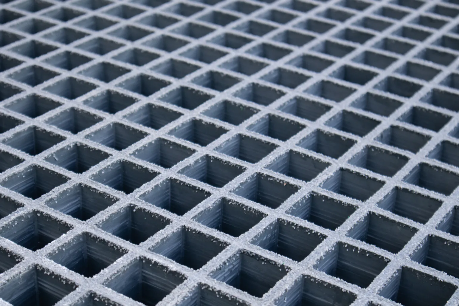What Is GRP Grating?
GRP grating systems are made by combining resin with glass fibres, the latter of which are laid out in a mesh grid pattern and then reinforced with resin to create a robust and highly long-lasting result.
This form of grating is known for being up to 75% lighter in weight than steel mesh grating, making it simpler to transport, handle, and install. It is also strong, and can support heavier loads, and it offers corrosion and rust resistance, making it well suited to installation in harsh facilities. Moreover, GRP grating can be fitted with gritted surfaces to provide slip resistance, and is chemical resistant as well, enabling its use in a variety of industrial settings.